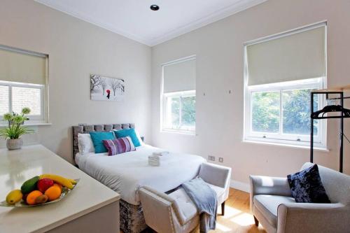 Un dormitorio con una cama y una mesa con un bol de fruta en Bright and cheerful studio, en Londres