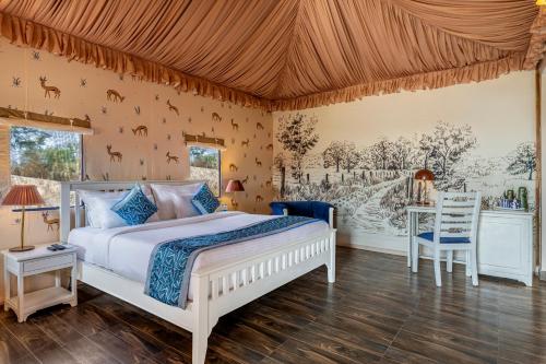 a bedroom with a white bed and a table and chairs at Sterling ReWild Sariska in Tehla