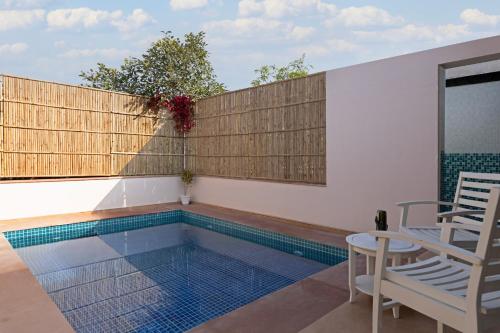 a swimming pool with two chairs and a table at Sterling ReWild Sariska in Tehla