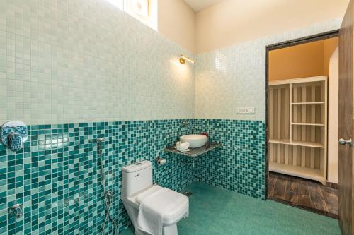 a blue tiled bathroom with a toilet and a sink at Sterling ReWild Sariska in Tehla