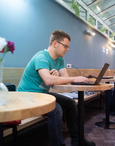 a man sitting at a table with a laptop at Safestay Bratislava Presidential Palace in Bratislava