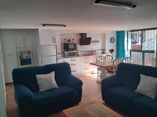 a living room with two blue couches and a kitchen at Alojamiento Casa Piano in Mairena del Aljarafe