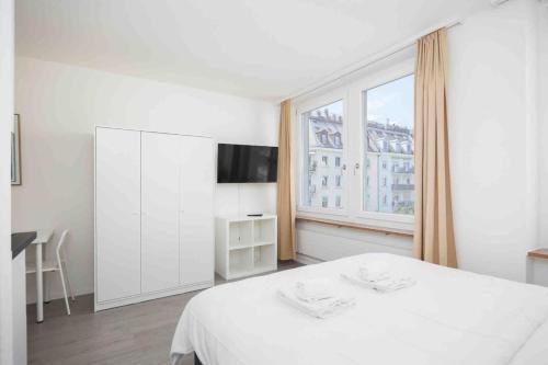 a white bedroom with a bed and a window at Downtown Deluxe Studio with Queen Bed BE-35 in Zurich