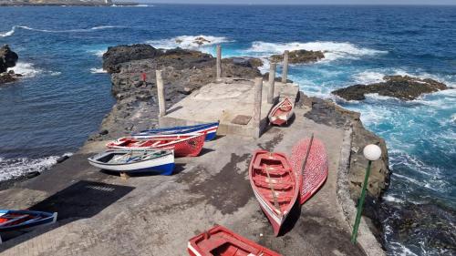a group of boats sitting on a rock wall near the water at chez albino guest house in São Filipe