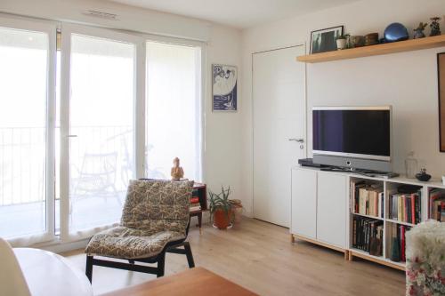 a living room with a tv and a chair at Lovely cozy cocoon at the gates of Paris in Romainville