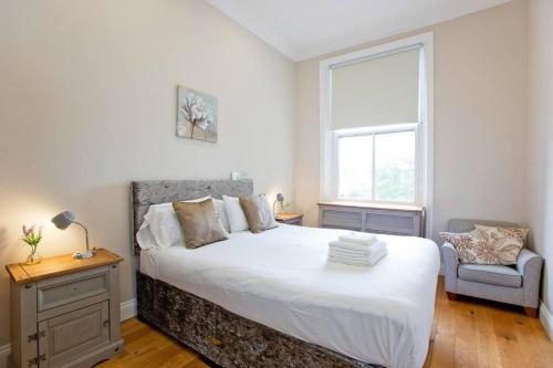 a bedroom with a large white bed and a chair at Stunning 1bed Kensington in London