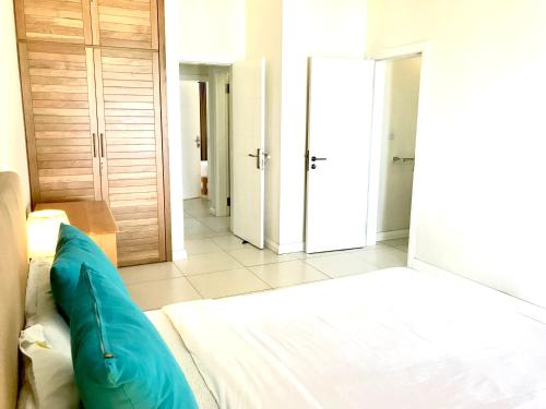 a bedroom with a bed with a blue pillow on it at Blue Lagoon seafront apartment in Flic-en-Flac