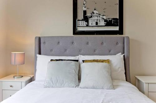 a bed with a black and white picture above it at Large 2bed Kensington in London