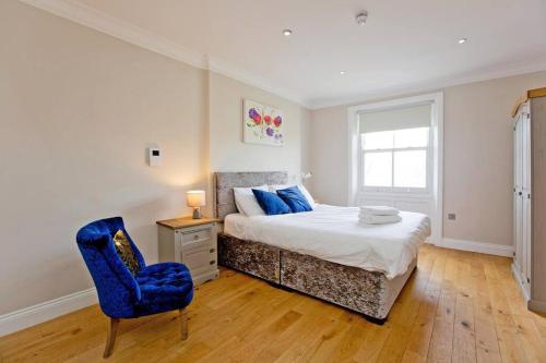 a bedroom with a bed and a blue chair at Super 2bed Kensington in London