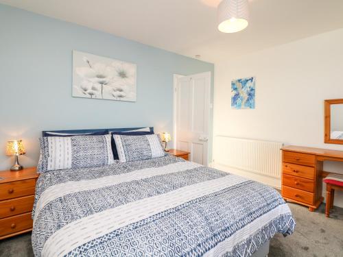 a bedroom with a blue and white bed and a desk at Quayside View in Brixham