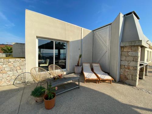 a house with two chairs and a bench on a patio at Les pieds dans l’eau in Sète