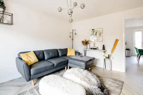 a living room with a black couch and a table at Stunning Private room in a Home - TV, Bathroom & Parking! in Manchester