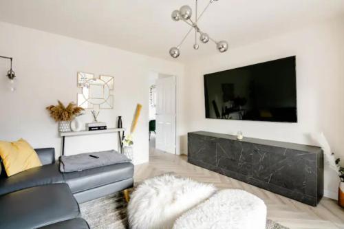 a living room with a black couch and a large screen tv at Stunning Private room in a Home - TV, Bathroom & Parking! in Manchester