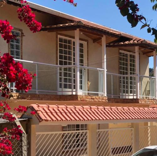 uma casa com varanda e flores vermelhas em Casa da Renata em São Lourenço