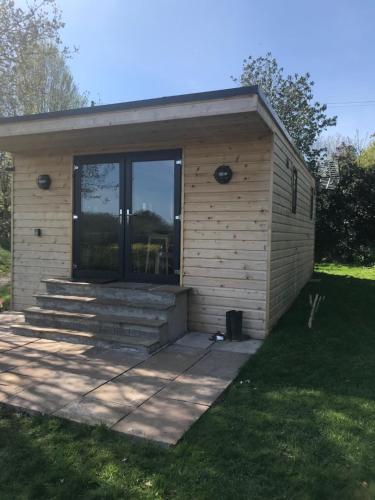a small building with a porch on a lawn at Secluded Log Cabin in beautiful private gardens in Broxwood