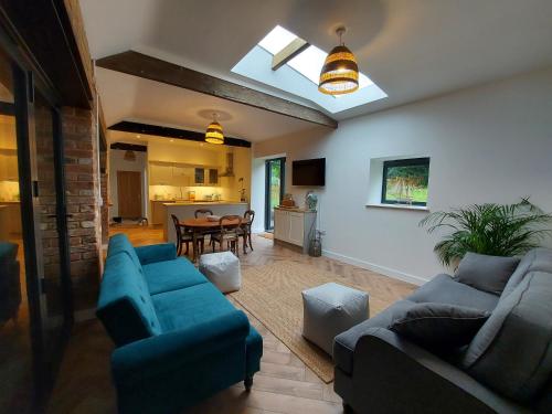 uma sala de estar com dois sofás azuis e uma mesa em Manor Farm Holiday Cottages em Chard