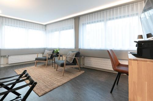 a room with a table and chairs and windows at INN JOY Apartments - Sankt Gallen Center in St. Gallen
