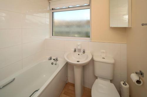 a white bathroom with a sink and a tub and a toilet at Henry's Guesthouse in Bath