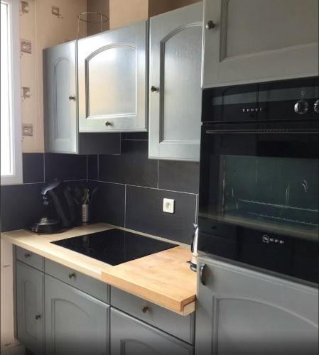 La cuisine est équipée de placards blancs et d'un four micro-ondes noir. dans l'établissement Maison confortable près de la plage de Châtelaillon, à Châtelaillon-Plage