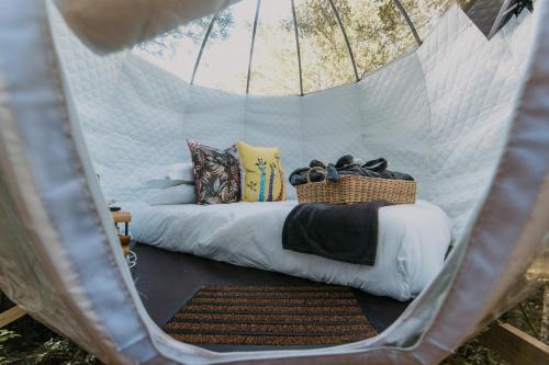 uma cama numa tenda com um cesto em The Cacoon by Once Upon a Dome @ Misty Mountain Reserve em Stormsriviermond
