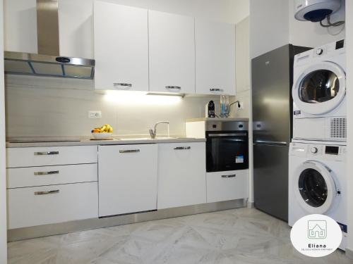 cocina con armarios blancos, lavadora y secadora en Eliana Deluxe & Modern Apartment, en Turín