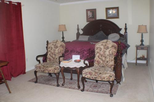 a bedroom with a bed with two chairs and a table at serenity hill bed and breakfast in Brownsville