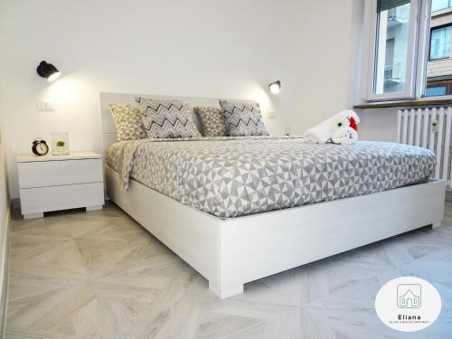 Eliana Deluxe & Modern Apartment في تورينو: سرير أبيض في غرفة نوم بيضاء وعليها كلب