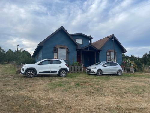 two cars parked in front of a blue house at Casa Sra Oti, Tipo Hostal con vista al mar Puerto Montt - CHINQUIHUE in Puerto Montt