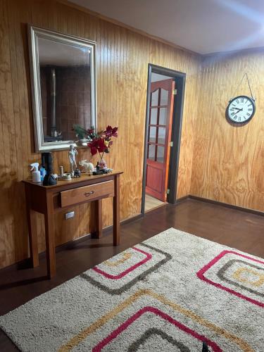 Habitación con mesa, espejo y mesa con alfombra. en Casa chinquihue vista al mar en Puerto Montt