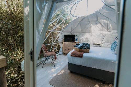 una camera da letto in un igloo con letto e scrivania di The Forest Dome by Once Upon a Dome @ Misty Mountain Reserve a Stormsriviermond