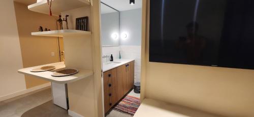a bathroom with a sink and a large television on the wall at Flat confortável próximo a praia! in Rio de Janeiro