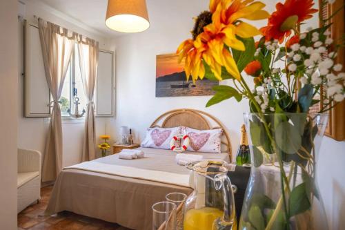 ein Schlafzimmer mit einem Bett mit Blumen in einer Vase in der Unterkunft Room in Holiday house - Relais Torre Chianca With Climate, Parking, Wi-Fi Panoramic Rooftop in Porto Cesareo