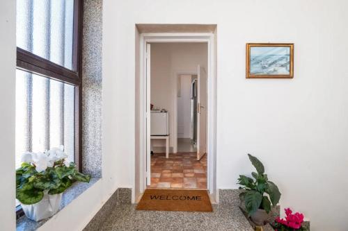 einen Flur mit einer Tür, die in ein Zimmer mit Blumen führt in der Unterkunft Room in Holiday house - Relais Torre Chianca With Climate, Parking, Wi-Fi Panoramic Rooftop in Porto Cesareo