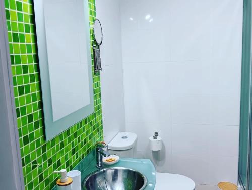 Baño de azulejos verdes con lavabo y aseo en Playa Velilla Velimar 2, en Almuñécar