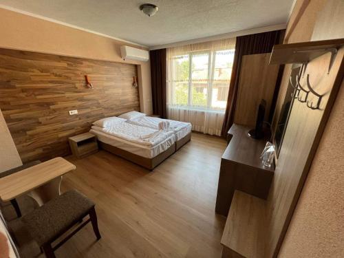 een slaapkamer met een bed en een houten muur bij Бонита Хотел Спа in Strelcha