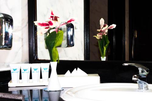 a bathroom sink with a vase of flowers in a mirror at White Valley Palace in Hurghada