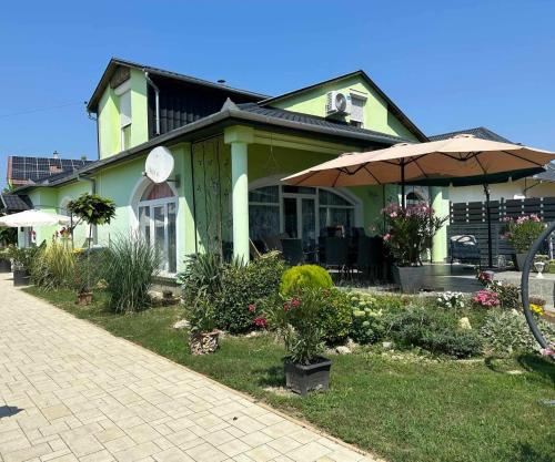 a green house with an umbrella and some plants at Rena Vendégház in Nagykanizsa