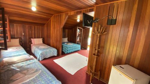 a room with two beds in a wooden room at Pousada Recanto da Giovana in Campos do Jordão