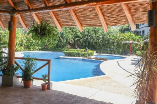 a swimming pool in a resort with palm trees at Palmas de Tamarindo 201D in Tamarindo