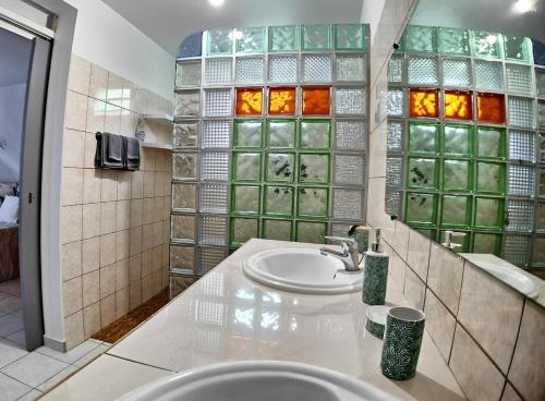 La salle de bains est pourvue d'un lavabo et d'une paroi en verre. dans l'établissement Couleurs caraïbes - Plage et Tranquillité, à Sainte-Anne