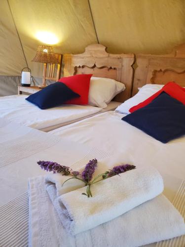 two beds in a tent with towels and flowers on them at Tiszaglamping, the belgian hideaway in Tiszacsege