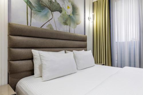 a bedroom with a bed with white pillows and a painting at Dem Premium Hotel - Round Trip Airport Service - Istanbul International Airport in Arnavutköy