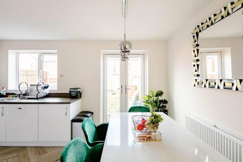 a kitchen with a white table and green chairs at Stunning Private room in a Home - TV, Bathroom & Parking! in Manchester