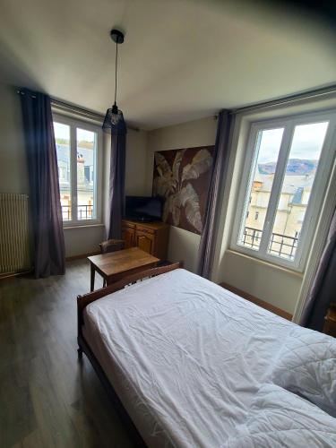 a bedroom with a large bed and two windows at Appartement confortable à La Bourboule, 64 m², balcons agréables in La Bourboule
