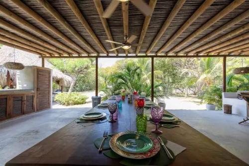 un comedor con una larga mesa de madera con platos y jarrones en Wonderful House Paradise in the Rosario Islands, en Cartagena de Indias