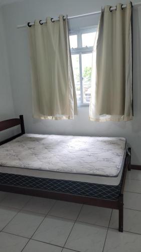 瓜拉派瑞Apartamento a poucos passos do mar的一张位于带窗户的房间的床