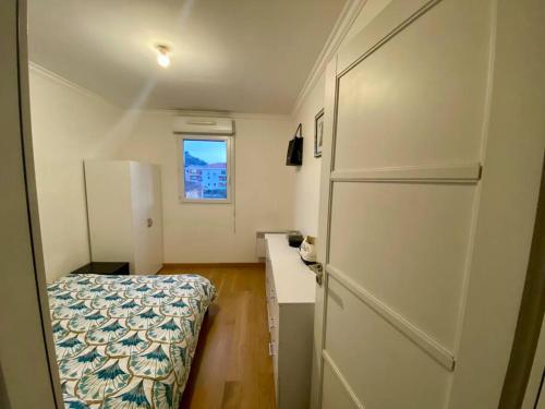 Kleines weißes Zimmer mit einem Bett und einem Schreibtisch. in der Unterkunft Nice Ouest St Isidore- 2P au calme in Nizza