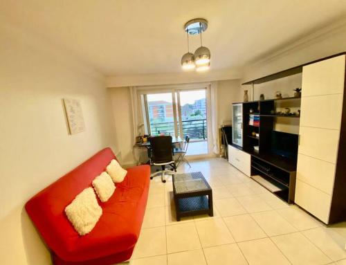 un salon avec un canapé rouge et une télévision dans l'établissement Nice Ouest St Isidore- 2P au calme, à Nice