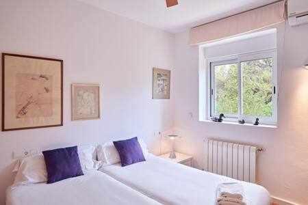 a white bedroom with a large bed with blue pillows at Can coll des cocons barefoot house 5min from pacha in Ibiza Town