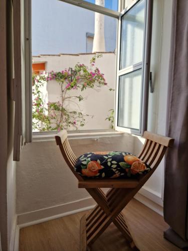 einen Stuhl mit einem Kissen vor einem Fenster in der Unterkunft Bea's Bed & Breakfast in Tavira